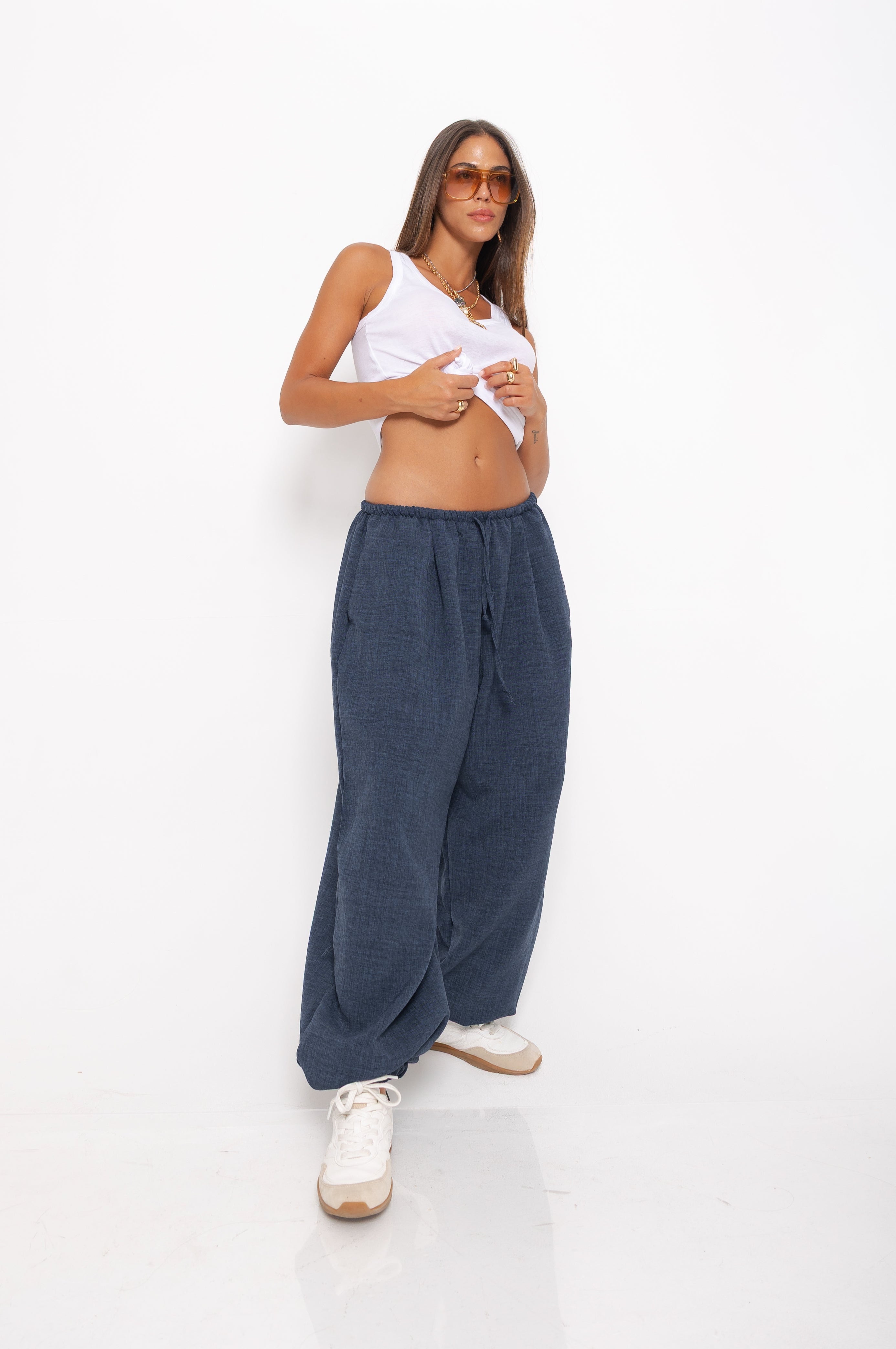 Woman wearing a white tank top and blue pants on a white background