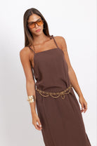 Woman wearing a brown dress with gold accents on a white background